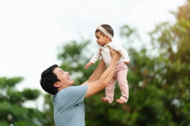 father holding and lifting with his infant baby in the park