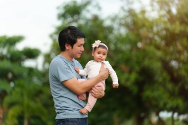 father holding and talking with infant baby in the park