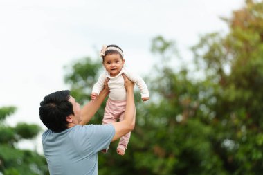 father holding and lifting with his infant baby in the park