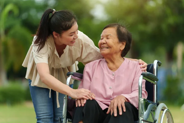 Glückliche Junge Enkelin Gespräch Mit Seniorin Rollstuhl Park lizenzfreie Stockfotos