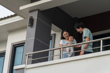 Anne ve baba, evlerinin balkonunda bebekle boğuşuyorlar. Mutlu aile 