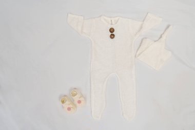 Beyaz bir yatakta bebek kıyafetleri ve aksesuarlar.