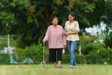 Torun ve yaşlı kadın parkta çim tarlasında bastonla yürüyorlar.