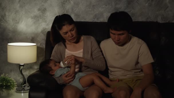 Напряженные Отец Мать Пытаются Кормить Бутылку Молока Плачущего Младенца Диване — стоковое видео