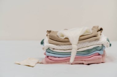 Yatağın üstüne yığılmış bebek kıyafetleri