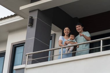 Mutlu aile (baba, anne ve bebek) evlerinin balkonunda
