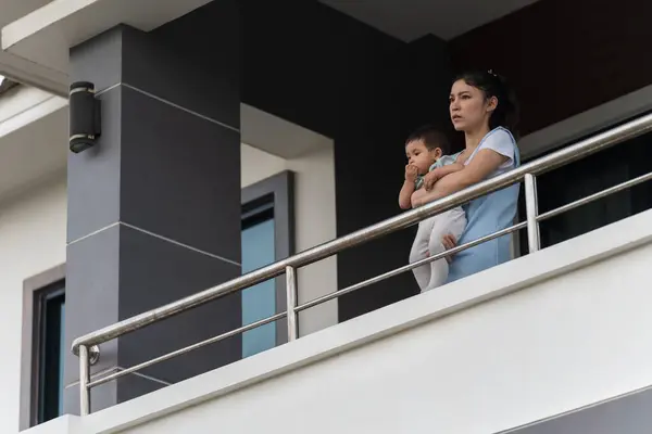 stressed mother and infant baby at balcony of their house