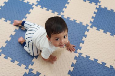 Oyun hasırı ya da yapboz zemininde emekleyen mutlu bebek manzarası