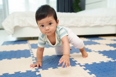Bebek paspasın üzerinde emekliyor ya da yatak odasındaki yapboz zemininde