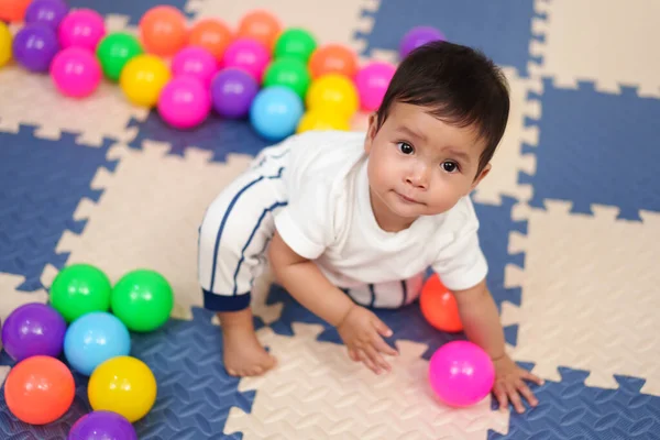 Bebek oyun parkında renkli plastik toplarla oynuyor