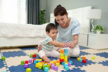 Mutlu bebek bebek, annesiyle tahta blok oyuncağı oynuyor. Yatak odasında yapboz minderiyle.