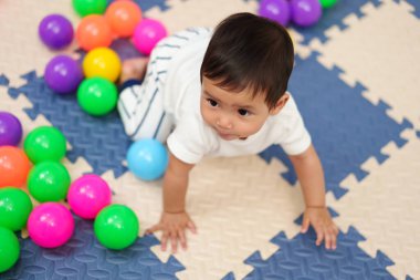 Bebek oyun parkında renkli plastik toplarla oynuyor