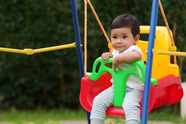Mutlu bebek bahçede salıncakta sallanıyor.