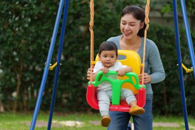Anne ve bebek bahçede salıncakta oynuyorlar.