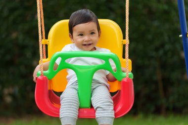 Mutlu bebek bahçede salıncakta sallanıyor.