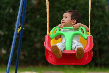 Mutlu bebek bahçede salıncakta sallanıyor.