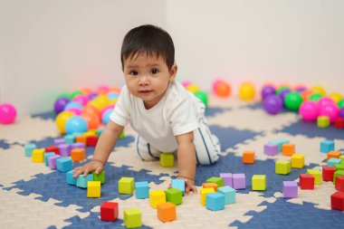 Bebek evde tahta blok oyuncağı oynuyor.