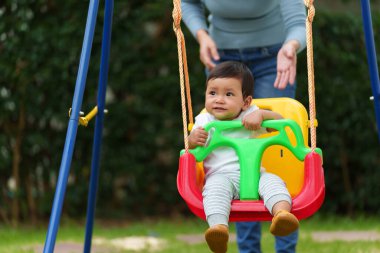Anne ve bebek bahçede salıncakta oynuyorlar.