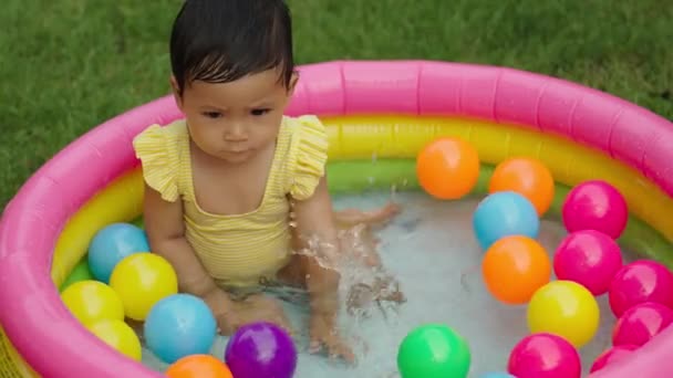 Menina Infantil Feliz Jogando Água Espirrando Com Bolas Plásticas Coloridas — Vídeo de Stock