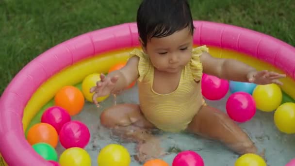 Menina Infantil Feliz Jogando Água Espirrando Com Bolas Plásticas Coloridas — Vídeo de Stock