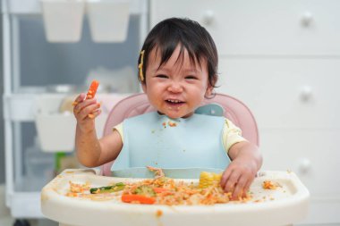 Mutlu bebek kendini besleyerek yemek ve sebze yiyor. Ya da bebek sandalyede sütten kesilmesine neden oluyor.