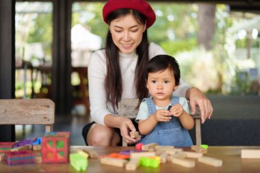 Yürüyen kız, annesiyle masada oyuncak oynuyor.