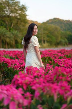Gelinlik giymiş güzel bir kadın çiçek açan noktalı çiçeklerin tadını çıkarıyor.