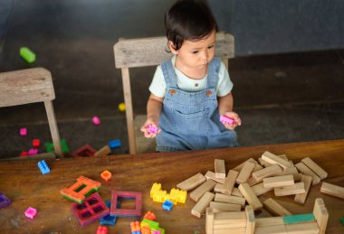 Küçük kız masada oyuncak oynuyor.