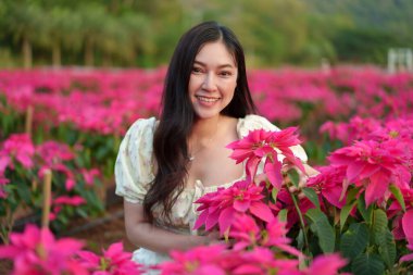 Gelinlik giymiş güzel bir kadın çiçek açan noktalı çiçeklerin tadını çıkarıyor.