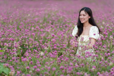 Çiçek açan pembe kürenin ya da bekarlığa veda çiçeği tarlasının tadını çıkaran elbiseli güzel bir kadın.