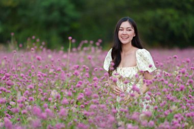 Çiçek açan pembe kürenin ya da bekarlığa veda çiçeği tarlasının tadını çıkaran elbiseli güzel bir kadın.