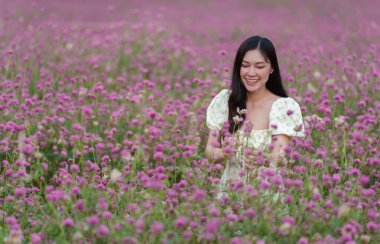 Çiçek açan pembe kürenin ya da bekarlığa veda çiçeği tarlasının tadını çıkaran elbiseli güzel bir kadın.