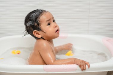 Mutlu bebek banyo yap ve evdeki küvette köpüklerle oyna.
