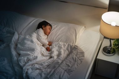 Küçük bebek geceleri bir yatakta uyuyor.