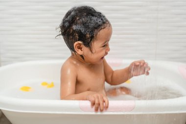 Mutlu bebek, banyo yap ve küvette duşun altında oyna.