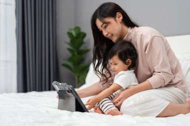 Bebekle anne yatakta dijital tablet bilgisayar kullanıyor.