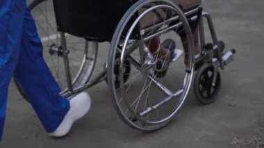 Tekerlekli sandalyedeki yaşlı kadının ayaklarını kapatın ve hemşire parkta ittirsin.