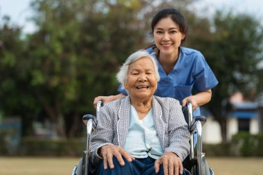 happy nurse take care and pushing senior woman in wheelchair at the park, friendly caregiver clipart