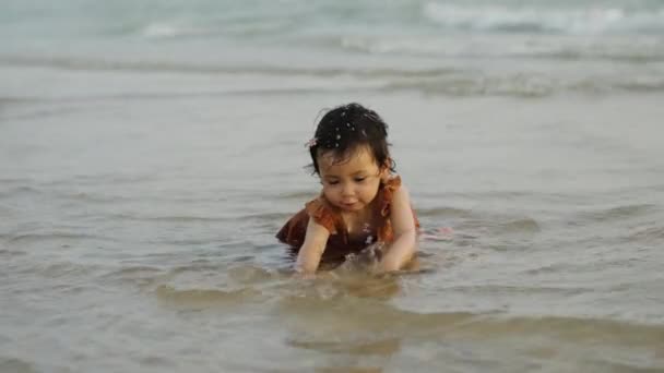 快乐的蹒跚学步的女婴在海滩上玩沙子和水 免版税图库视频