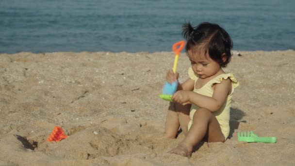 快乐的蹒跚学步的小女孩在海滩上玩沙玩具 视频剪辑