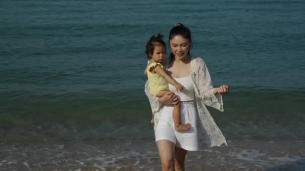 海のビーチで彼女の幼い赤ん坊と抱き 歩いている母親のゆっくり動き ロイヤリティフリーストック映像