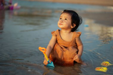 Mutlu bebek kız deniz sahilinde oyuncak ve su oynuyor.