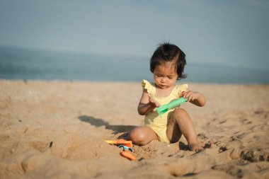 Mutlu küçük kız deniz sahilinde kum oyuncağı oynuyor.