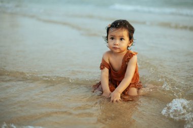 Mutlu küçük kız deniz sahilinde kum ve su oynuyor.