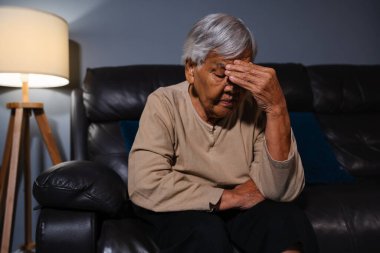 Son sınıf öğrencisi kadın geceleri oturma odasında kanepede otururken baş ağrısı çekiyor.