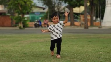 Parktaki çim tarlasında koşan mutlu küçük kızın ağır çekimde