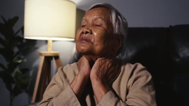 老年妇女晚上坐在客厅的沙发上 脖子疼 — 图库视频影像