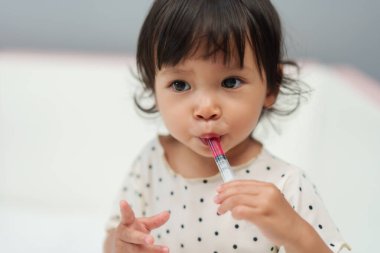 Bebek şırıngayla şurup ilacını tek başına alıyor. Hasta çocuk.