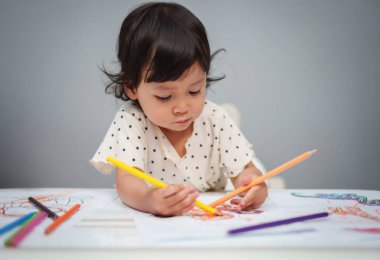Bebekler masada renkli kalemle resim çizmek için oynuyorlar.