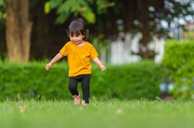 Parkta koşan mutlu küçük kız.